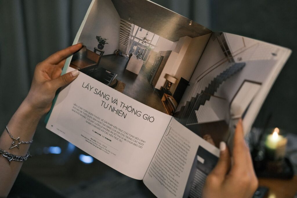 Home Close-up of hands holding a magazine featuring modern interior design.