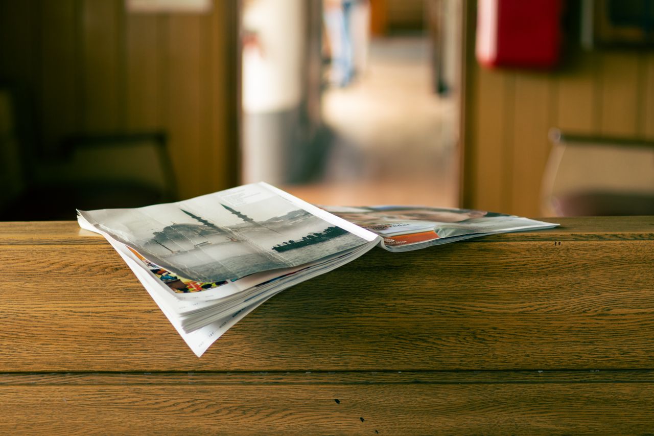 Stack of magazines on a wooden table in a cozy indoor environment.