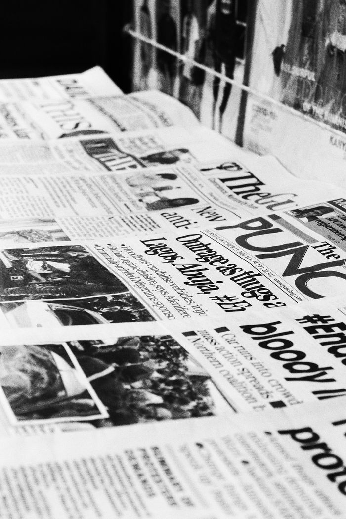 get-in-touch A detailed close-up of Nigerian newspapers in a monochrome format showcasing headlines and articles.