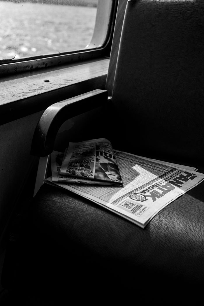 A newspaper rests on a ferry seat in İstanbul, captured in black and white.
