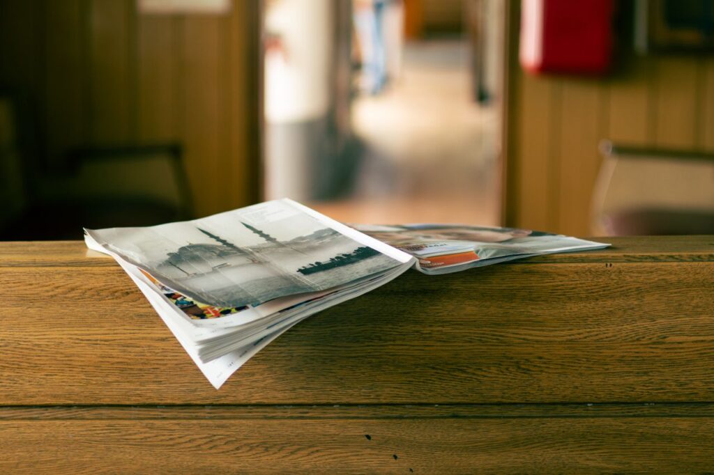 Stack of magazines on a wooden table in a cozy indoor environment.
